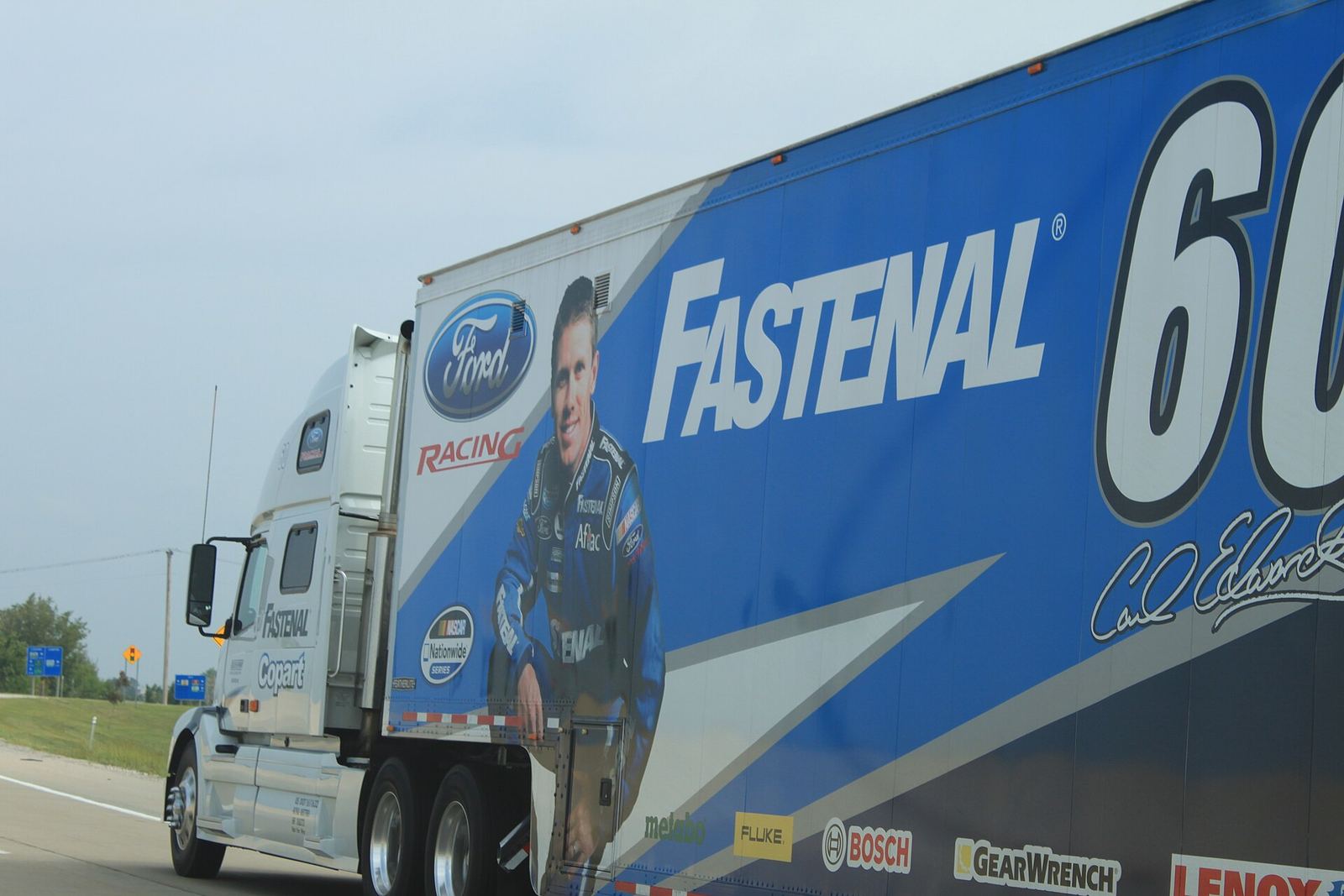 A Fastenal Racing transporter truck on a highway, with Carl Edwards and the No. 60 on the trailer