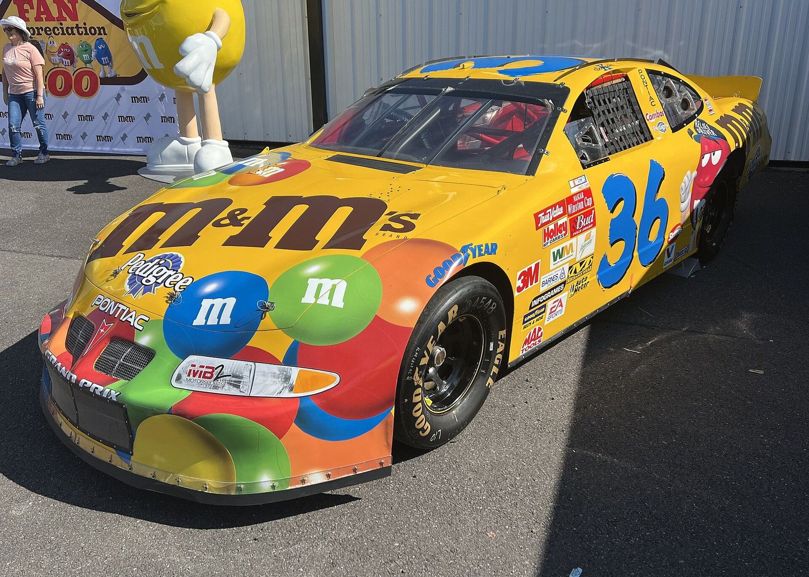 Ken Schrader's yellow No. 36 M&M's Pontiac covered in candy graphics, displayed as a show car