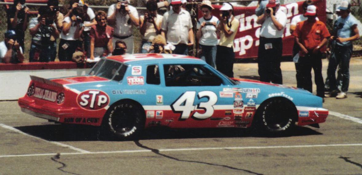 Richard Petty's No. 43 STP Pontiac in front of a crowd of photographers and fans