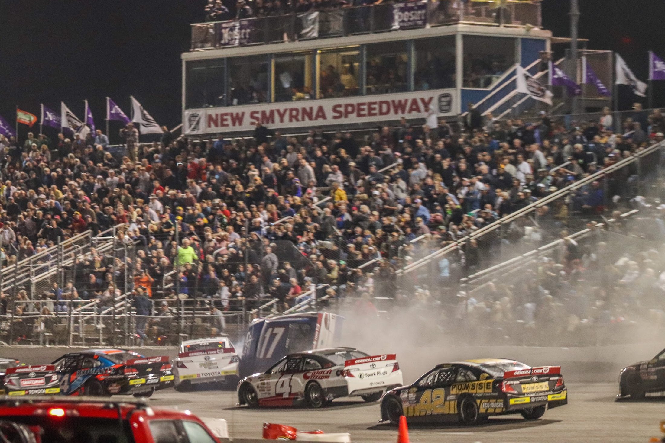 Packed grandstands at New Smyrna Speedway as the field races by